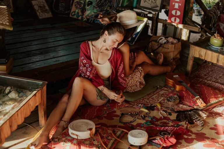 young women sitting back to back on a wooden floor of a souvenir store