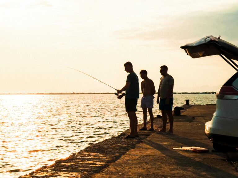 silhouette of three men fishing at sunset
