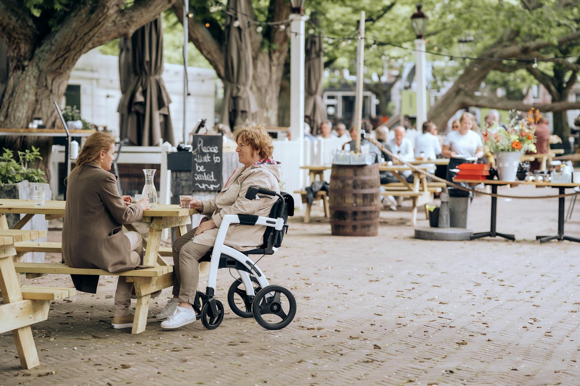 senior woman on wheelchair sitting at table with friend